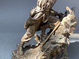 bronze statue of a man on a rock with a staff