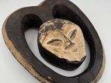 une image représentant une sculpture en bois représentant un visage sur une surface blanche