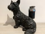 a black dog statue next to a lighter on a table