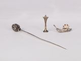 two silver objects are sitting on a white surface, one is a spoon and the other is a spoon and