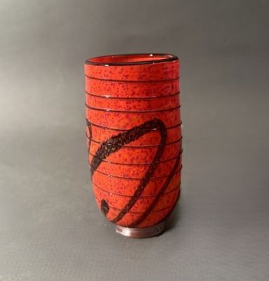 un vase rouge orné d'un motif noir