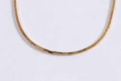 gros plan d'un collier en or sur une surface blanche
