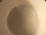 a white bowl with a black rim sitting on a wooden table