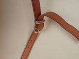 tan leather strap on a white purse with a gold buckle