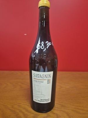 une bouteille de vin posée sur une table, avec un mur rouge en arrière-plan