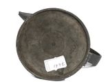 an old metal pan with a tag on it sitting on a white surface