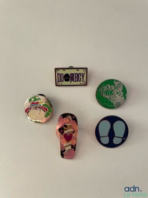 three pin badges of various sizes and shapes on a white surface