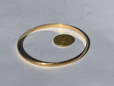 a gold ring with a coin in it on a white surface