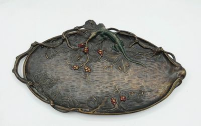un plateau en métal orné d'un oiseau, posé sur une surface blanche