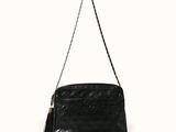 un sac à main noir muni d'une bandoulière en chaîne et d'un pompon