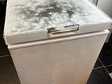 a small white refrigerator sitting on the floor in the kitchen