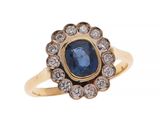 gros plan d'une bague en or avec un saphir et des diamants