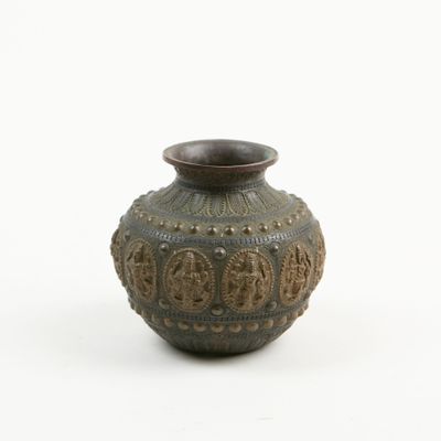 un petit vase posé sur une surface blanche