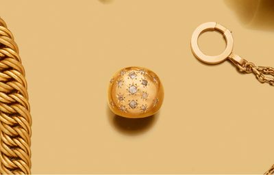 une photo montrant un collier en or et une boule en or posés sur une table