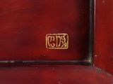 a close up of a red clock with gold lettering on it