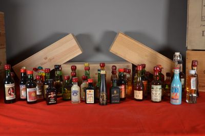 many bottles of alcohol sitting on a table with a red table cloth