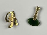 two pieces of gold and green jewelry on a white surface