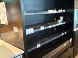 un réfrigérateur vide dans un magasin où de nombreuses étagères sont vides