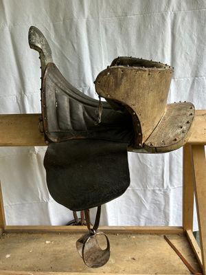 a horse saddle on a wooden stand with a hat on top of it