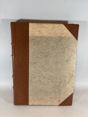 un vieux livre à la couverture marron posé sur une table blanche