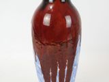 a red and blue vase sitting on a white surface