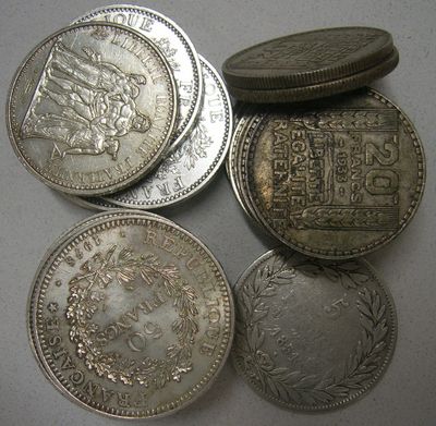 quatre types différents de pièces d'argent sur une surface blanche