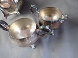two silver teapots sitting on a table next to each other