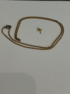 gros plan d'un collier en or avec une chaîne sur une surface blanche