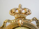 une horloge en or surmontée d'une couronne