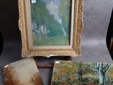 trois tableaux représentant des arbres sont exposés sur une table, à côté d'un chevalet