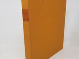 an orange book sitting on top of a white table next to a white wall