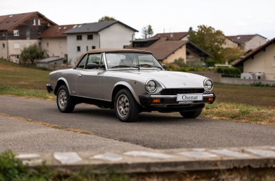 une voiture argentée qui roule sur la route devant une maison