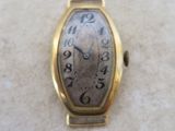 une montre en or posée sur une surface blanche