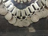 a necklace made of silver coins on display in a glass case