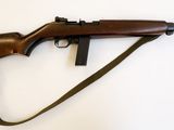 un fusil muni d'une sangle, posé sur une surface blanche