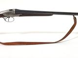 fusil exposé sur un fond blanc, avec des lunettes transparentes posées dessus