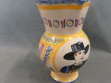 a yellow and blue vase with a picture of a man on it
