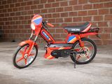 a small red motorcycle parked in front of a brick wall