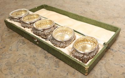 quatre bols en argent dans une boîte verte posée sur une table