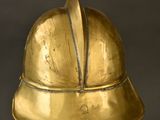 brass helmet on a stand against a black background