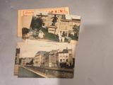 plusieurs vieilles cartes postales représentant des bâtiments et une statue, posées sur une table