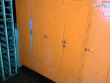 orange lockers are lined up in a dark room with a ladder