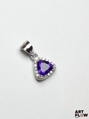 un gros plan d'un pendentif violet en forme de cœur posé sur une surface blanche