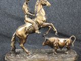 statue of a man on a horse with a bull in the foreground