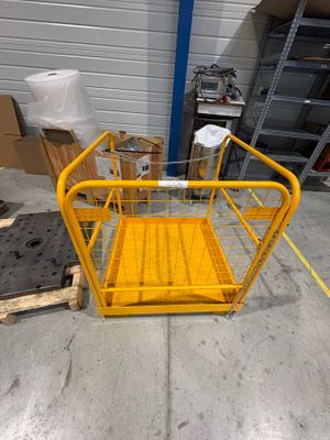 un gros plan d'une cage jaune posée sur une palette dans un entrepôt