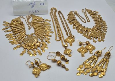 quelques bijoux en or sont posés sur une surface blanche