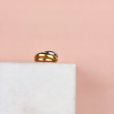 un gros plan d'une bague en or et en argent posée sur un bloc de marbre