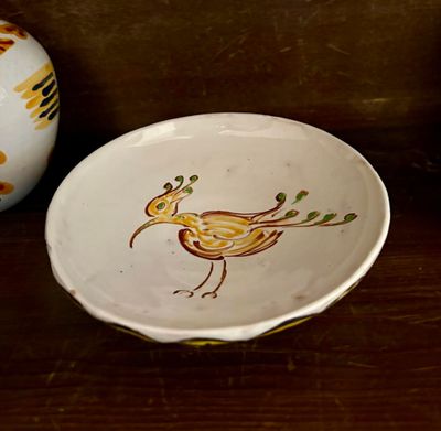 une assiette sur laquelle est peint un oiseau, à côté d'un vase