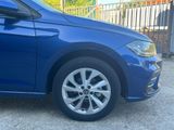 the front end of a blue car parked in front of a fence
