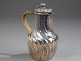 a silver pitcher with a gold handle on a table